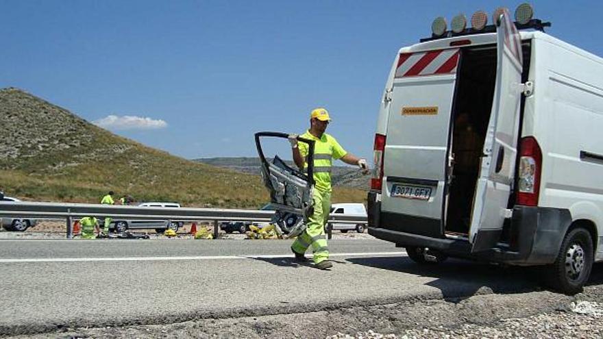 Arriba un operario de Carreteras retirando los restos del accidente y abajo el equipo de Atestados de la Guardia Civil y las largas colas.