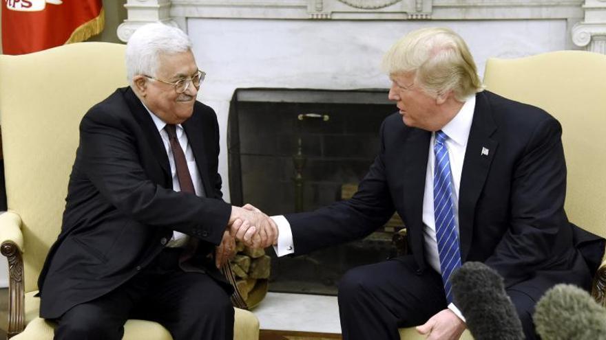 Los presidentes palestino y estadounidense se dan la mano.