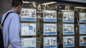 Un joven consulta los carteles de una inmobiliaria en Barcelona.