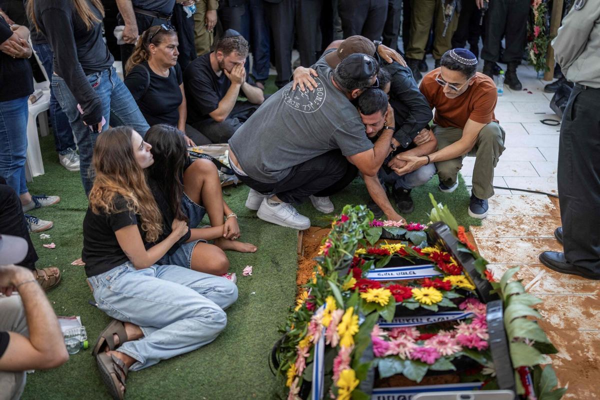 Relatives and family members mourn at the grave of Israeli army Major Yuval Ezra, 27, killed in the Israeli-occupied Palestinian West Bank, during his funeral in Bet Dagan, central Israel on July 26, 2026. The Israeli military said on June 24, 2026, that a second Israeli, Yuval Ezra, had been killed during a violent confrontation between Israelis and Palestinians in the area of the village of Tell in the Israeli-occupied West Bank. The occupied West Bank has been gripped by almost daily violence involving Israeli troops and settlers since the start of the Gaza war in October 2023. (Photo by ilia YEFIMOVICH / AFP)