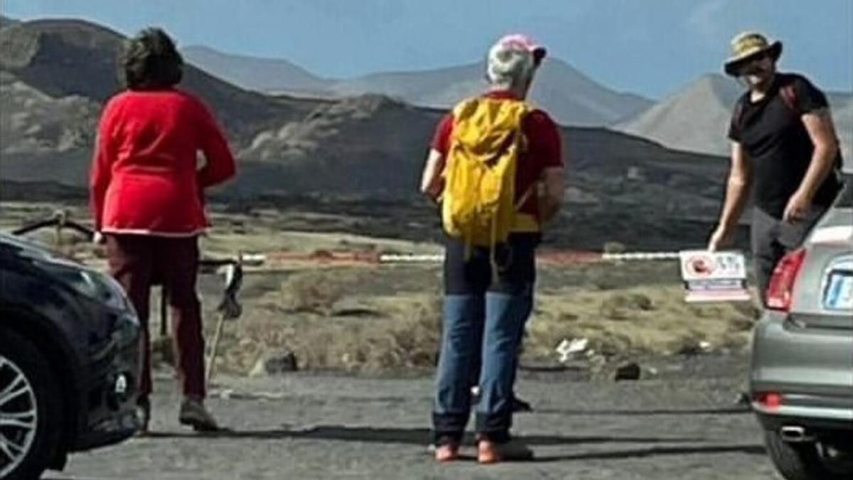 Turistas junto al cartel que prohíbe el acceso al Volcán del Cuervo
