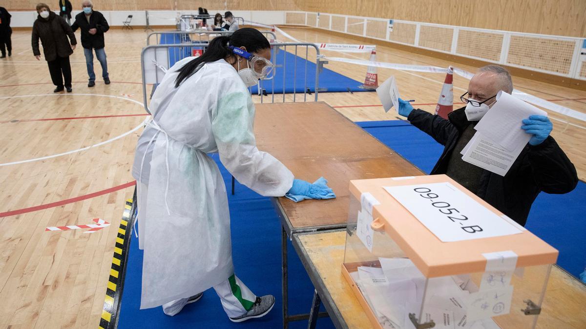 Una mujer desinfecta una mesa de votación en Barcelona