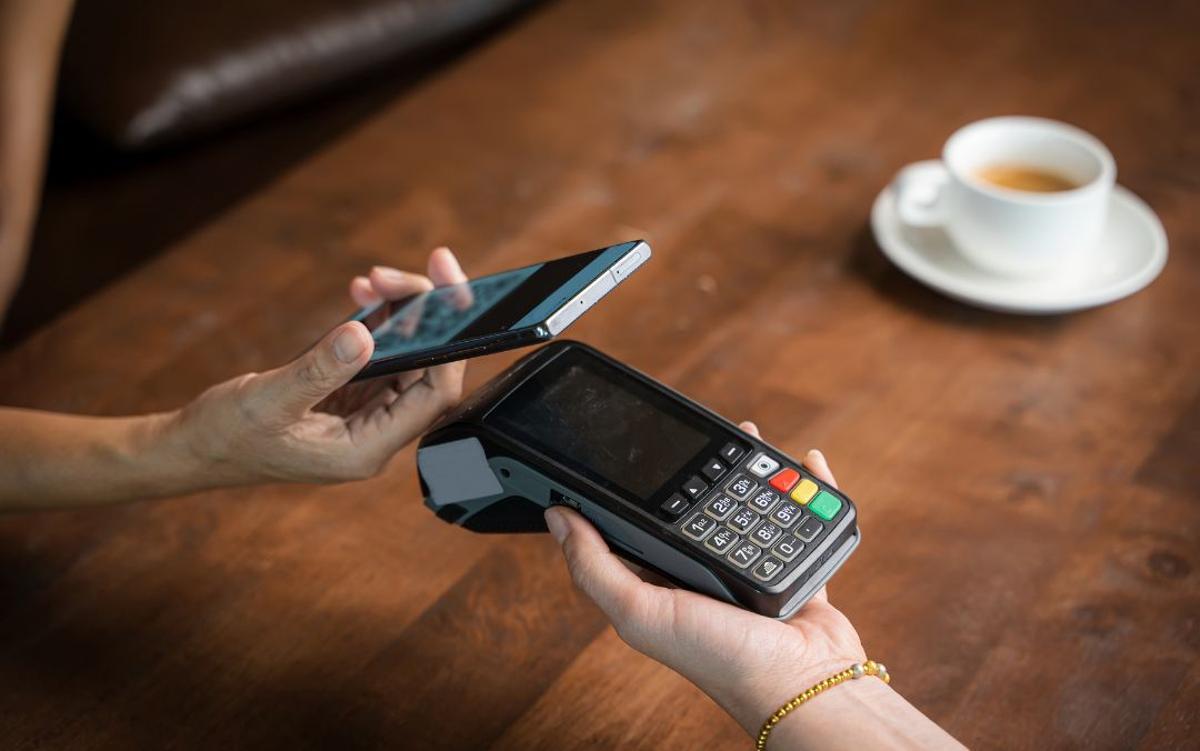 Imagen de recurso de una persona pagando un café con el móvil.