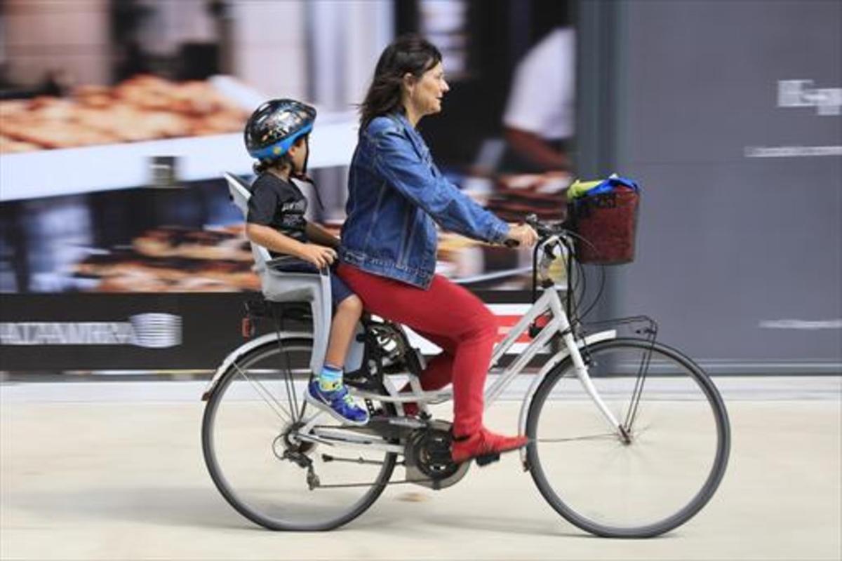 Una madre lleva a su hijo en bicicleta en el Poblenou.