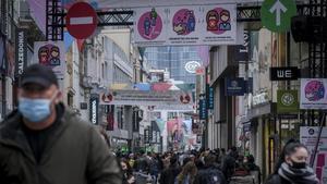 Ciudadanos con mascarila pasean por una calle comercial de Brusleas, este miércoles.