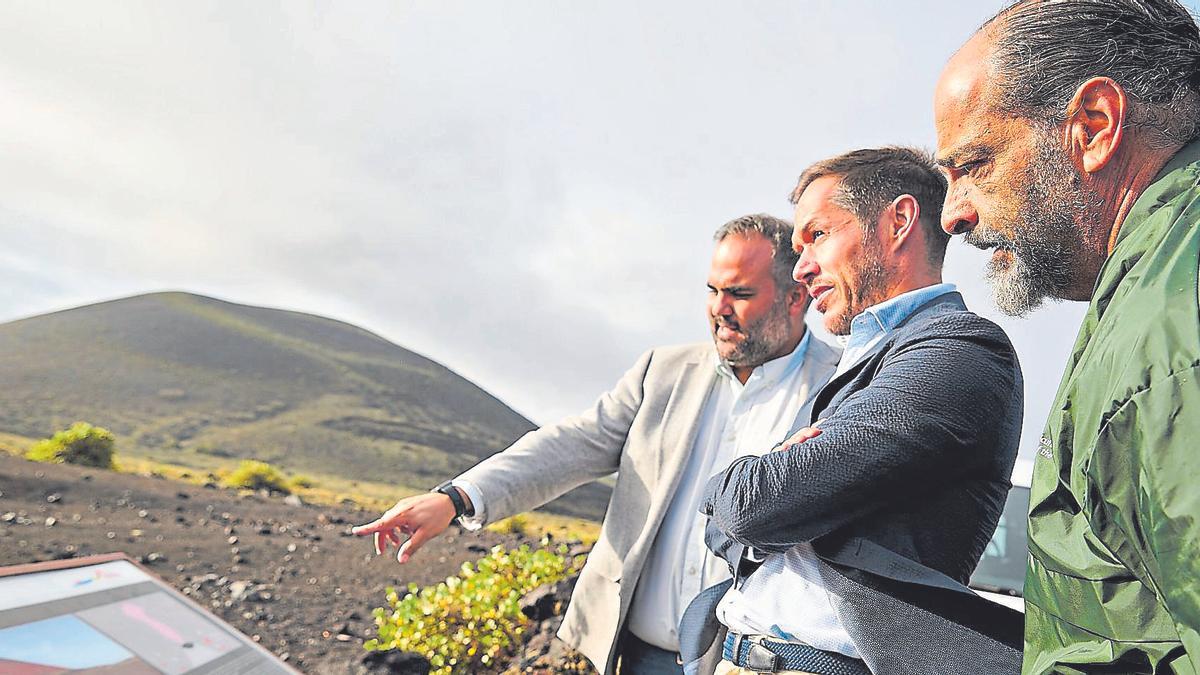 Mariano Hernández Zapata,  en el centro, atiende las explicaciones de Samuel Martín sobre el Parque Natural de Los Volcanes.