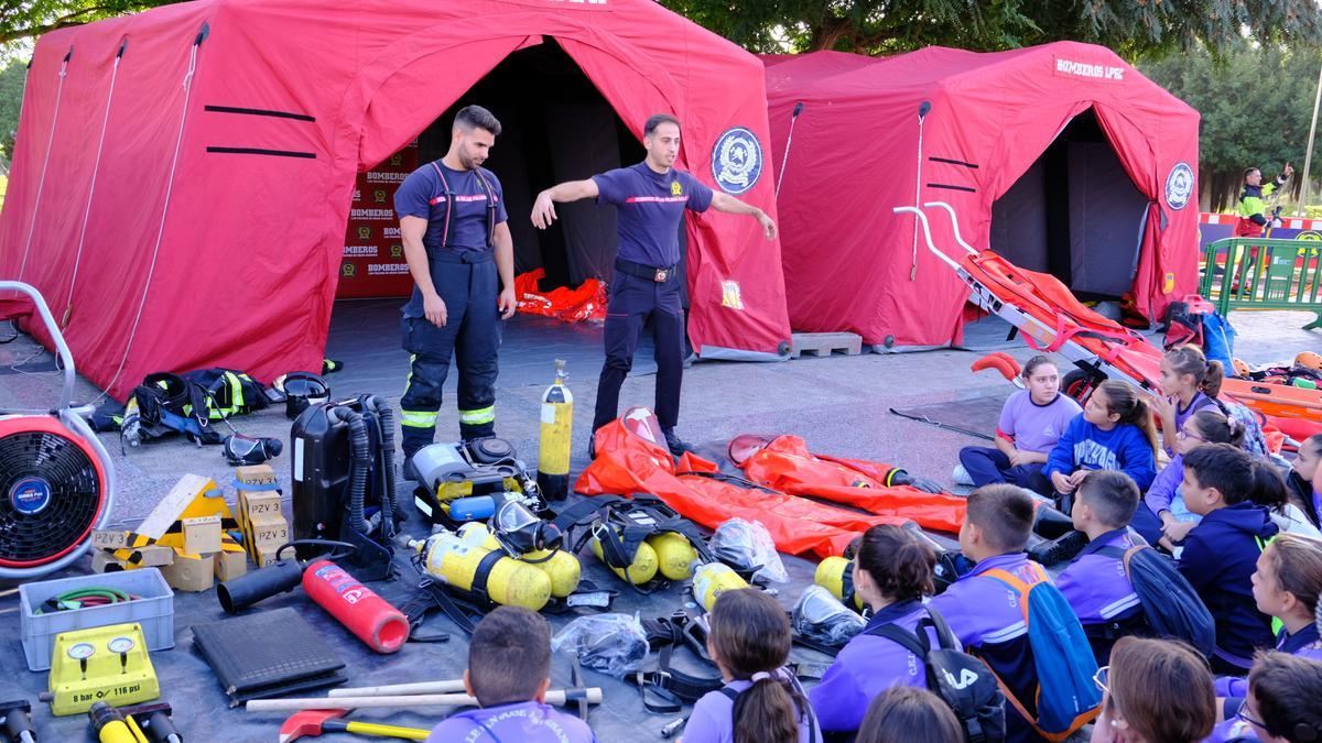 Alumnos observan la explicación de los bomberos sobre las vestimentas que utilizan