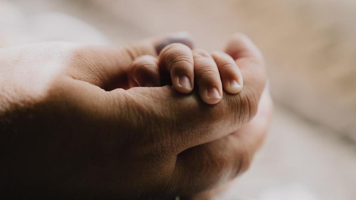 Un progenitor sostiene la mano de un pequeño.