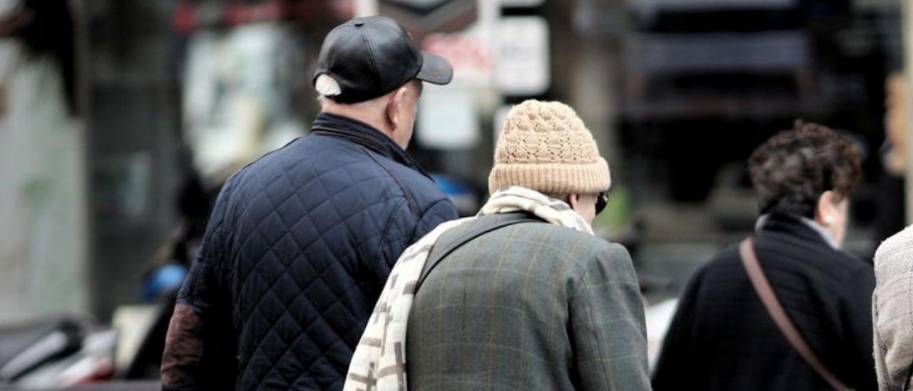 Personas mayores, paseando por una calle.