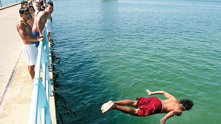 Un joven se lanza al agua desde el puente de Toralla; frente a la playa del Vao.