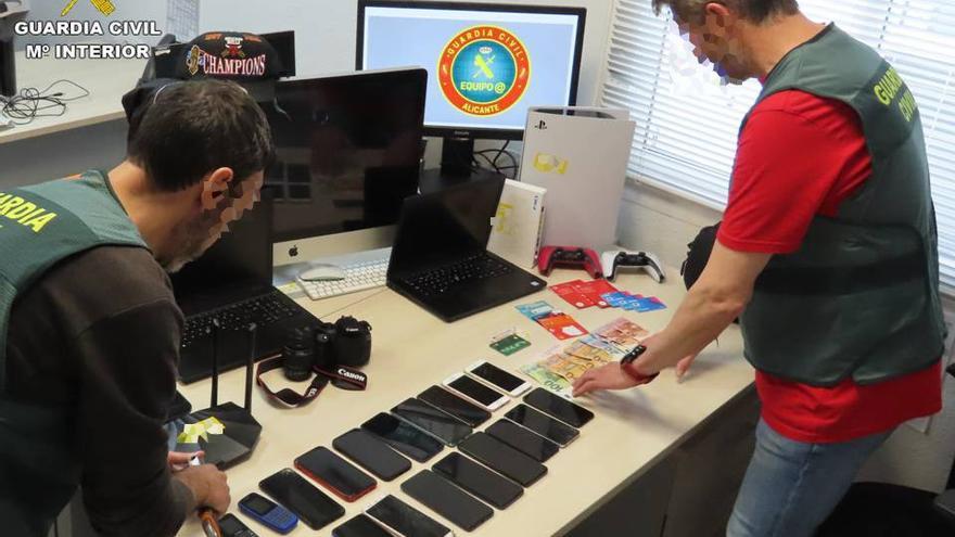 Dos agentes de la Guardia Civil revisan los teléfonos sustraídos.