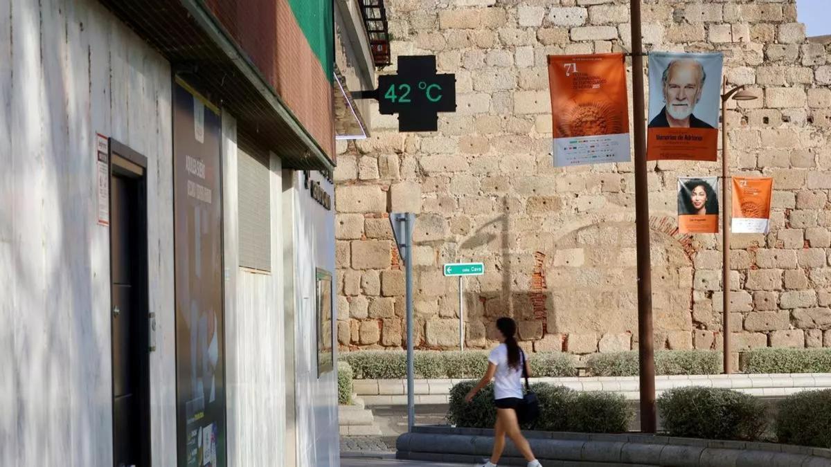Una viandante camina por una calle de Mérida junto a un termómetro que marca 42 grados.