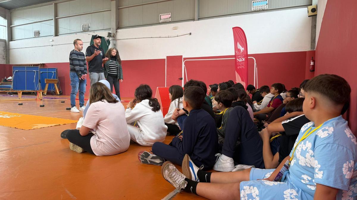 Víctor Riobó, flanqueado por Álex Vidal e Nucha Brión, con alumnos do CEIP O Grupo.