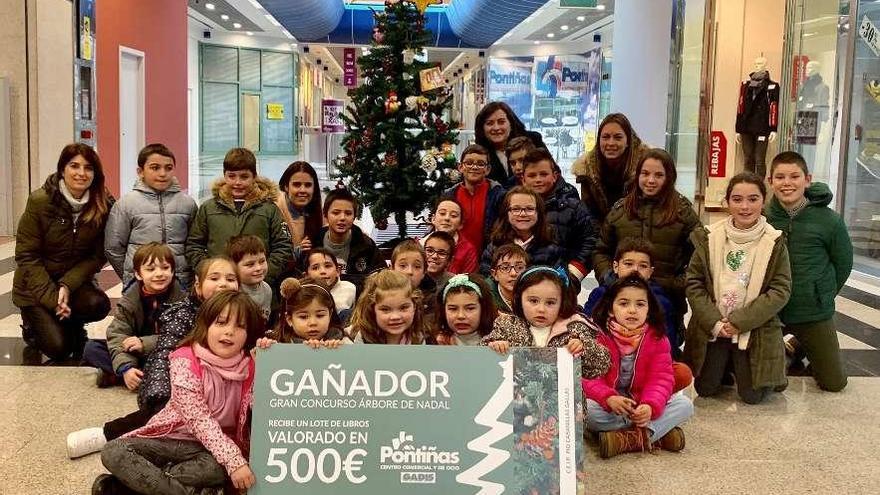 Alumnado y docentes, ayer, en el centro comercial durante la entrega del premio, con el árbol al fondo.