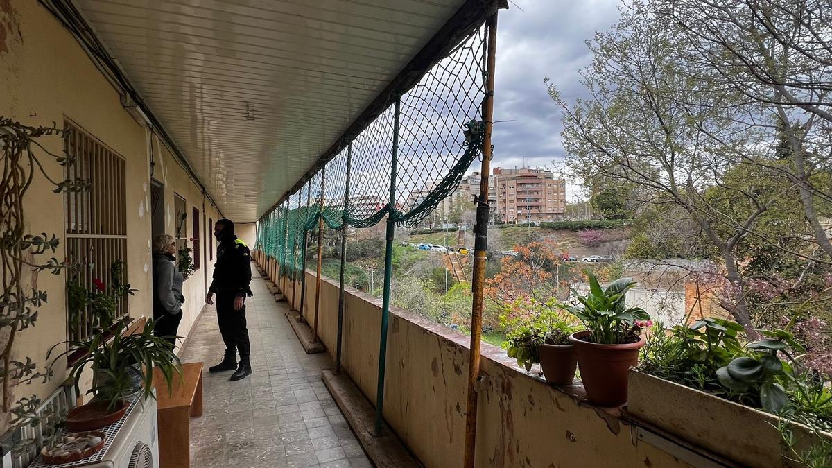 Un agente de la Policía Local charla con una de las vecinas que permanece en su casa, pese al riesgo de derrumbe que pesa sobre el edificio de Esplugues conocido como 'El Barco'