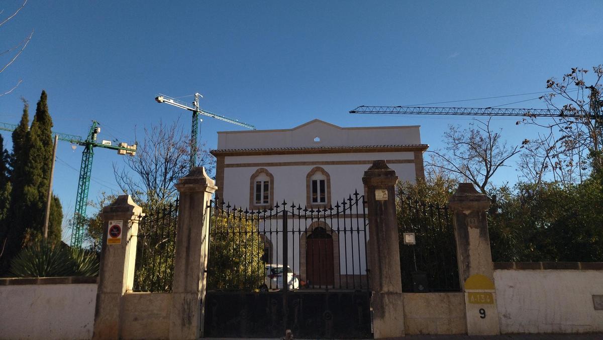 La histórica casa de bella arquitectura ecléctica y, a su espalda, las grúas