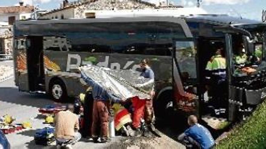 Els equips d&#039;emergències, treballant al lloc del succés, i el vehicle, encastat contra el mur i dins la cuneta.