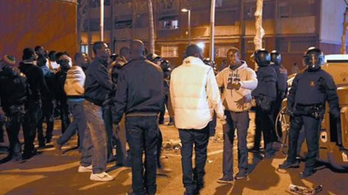 Un grupo de senegaleses, frente a antidisturbios de los Mossos d'Esquadra, en la calle de Ferrer Bassa, ayer.