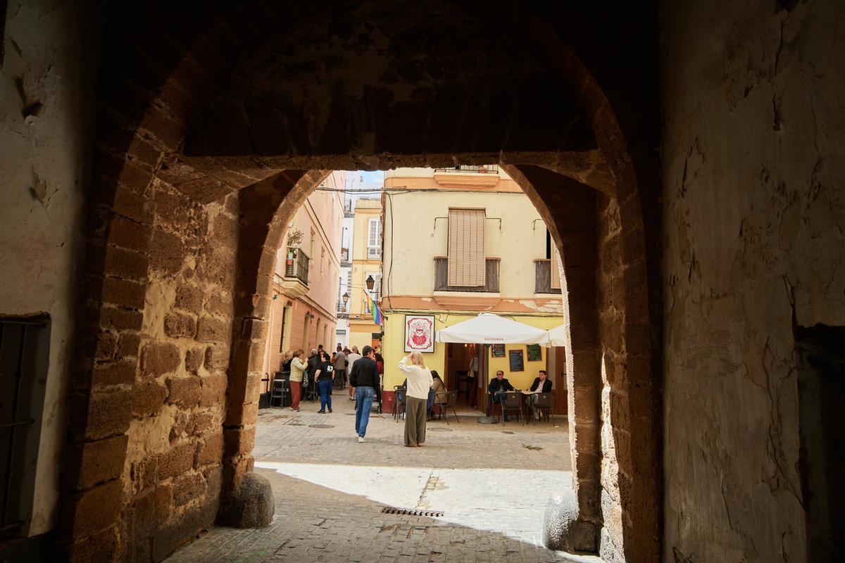 Vista a través del Arco del Pópulo hacia el café La Mariquita Mala en el casco antiguo de Cádiz, España