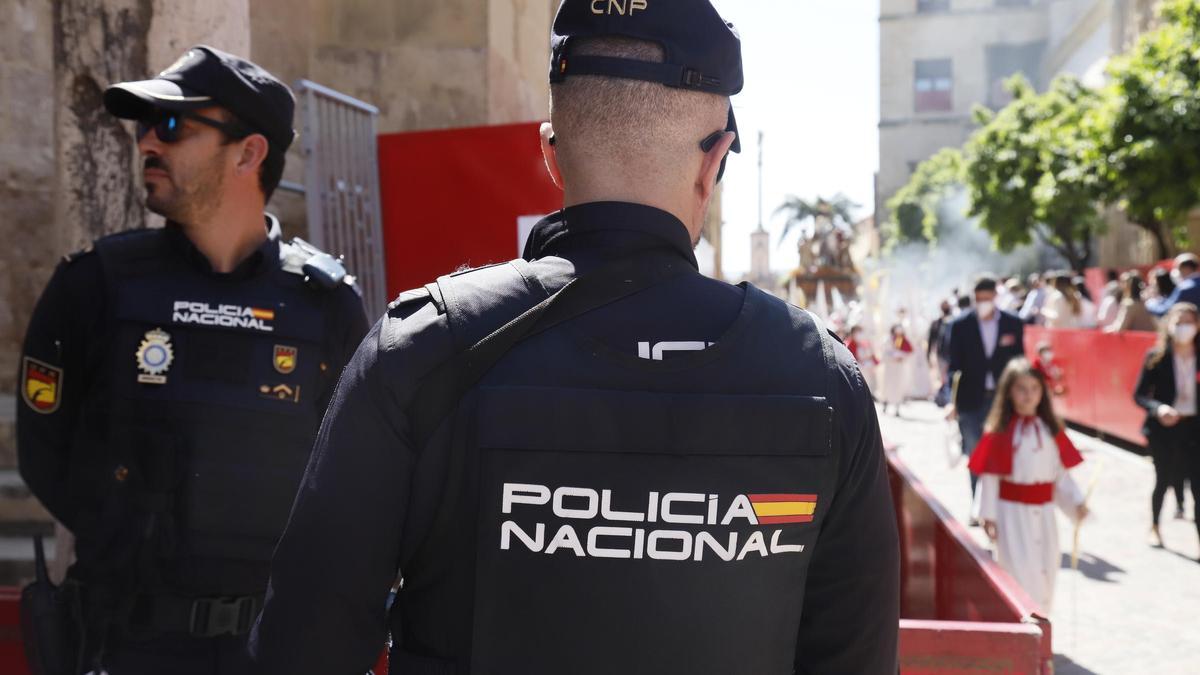 Dos policías nacionales durante la entrada de la Borriquita a la Mezquita-Catedral de Córdoba, en una edición anterior de la Semana Santa.