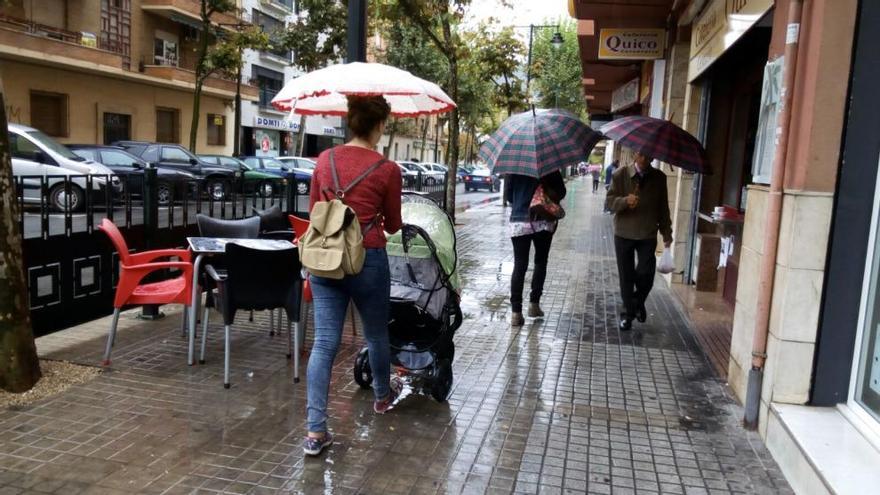 Paseantes con paraguas en una calle de Alcoy