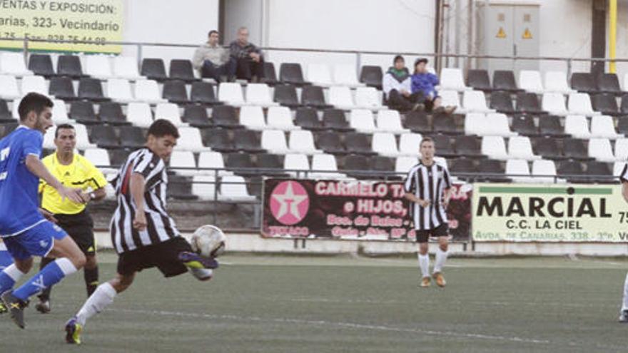 Tana frena el balón próximo a dos defensas del Tenerife B.  i DEL ROSARIO