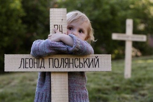 A child embraces one of the 107 wooden crosses, which honour victims of recent protests in Ukraine in Prague