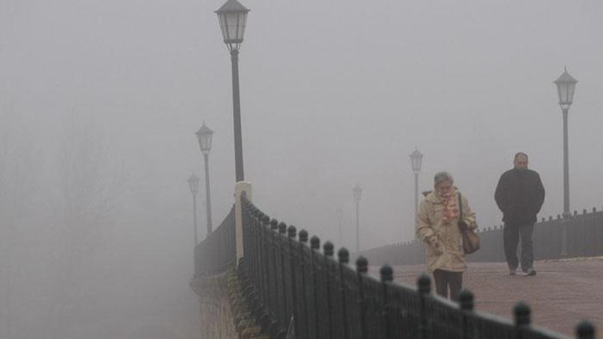 Varias personas cruzan el Puente de Piedra de Zamora bajo la niebla