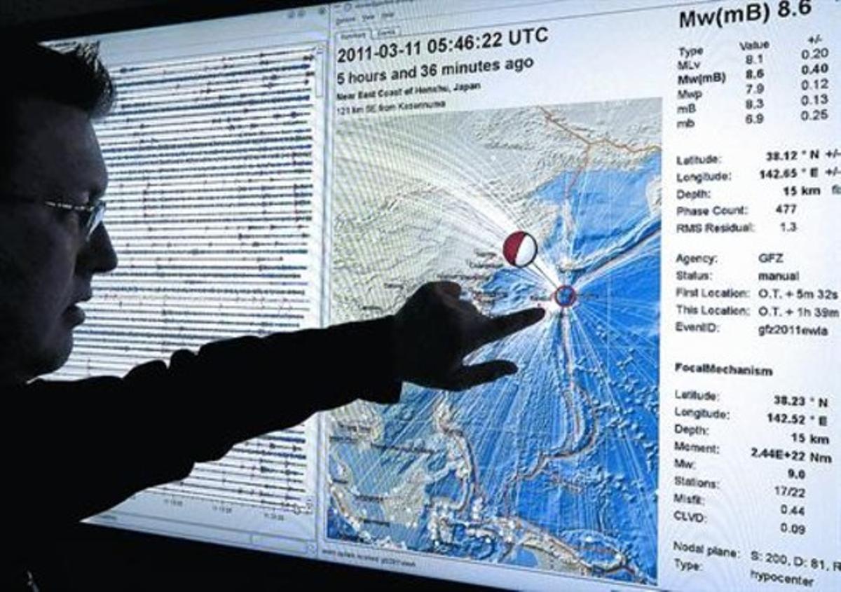 Un especialista del Servei Geològic Britànic analitza sobre un mapa la ubicació del terratrèmol de Sendai.