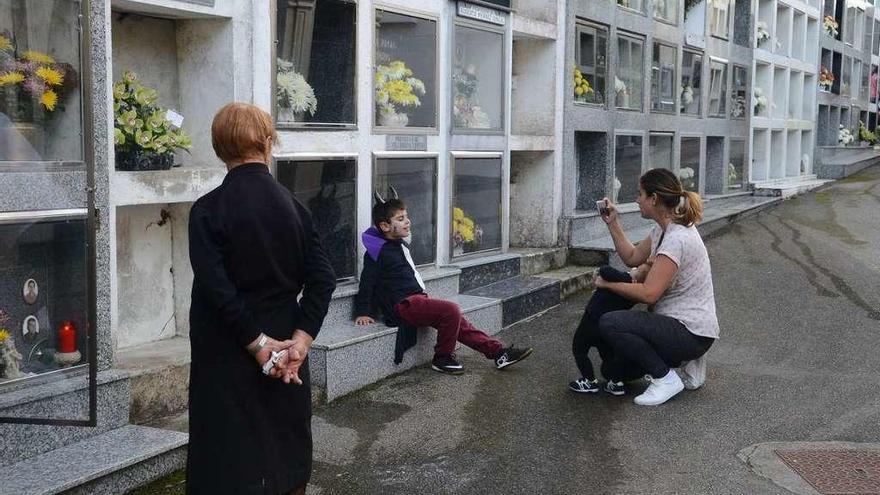 Una familia conjuga el Samaín con la celebración de difuntos, ayer, en el cementerio de Bueu. // G.N.