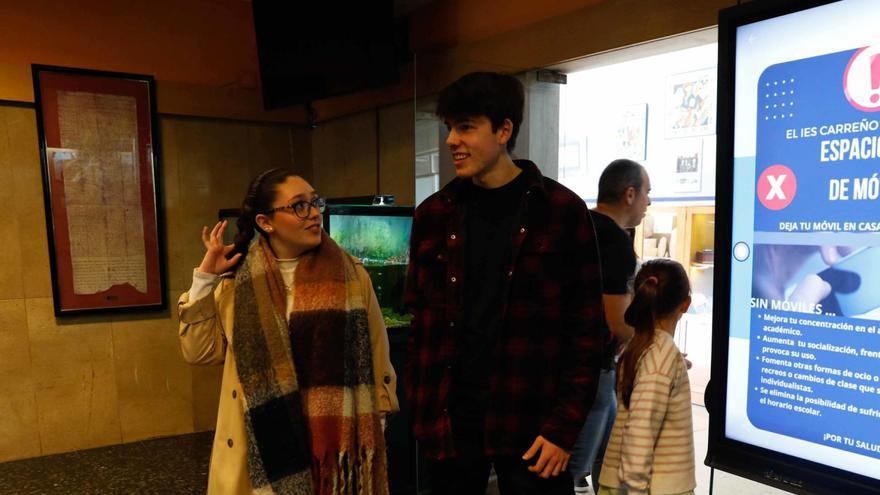 Noa Fernández y Darío Pérez, en el IES Carreño Miranda de Avilés, junto a un cartel que prohíbe los móviles. | Mara Villamuza