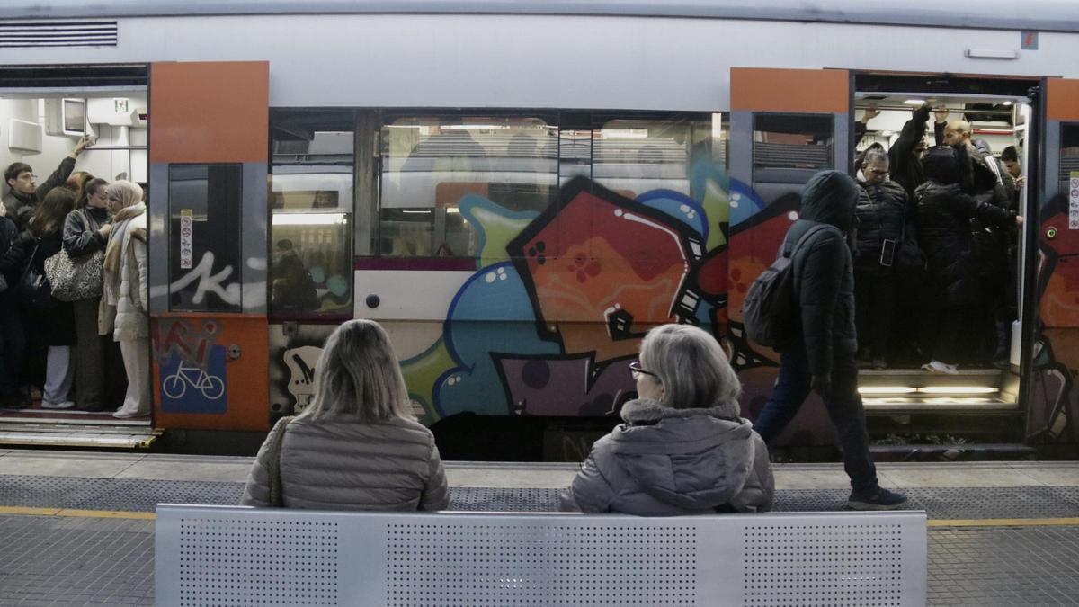 Dues usuàries de Rodalies assegudes a un banc d'una estació.
