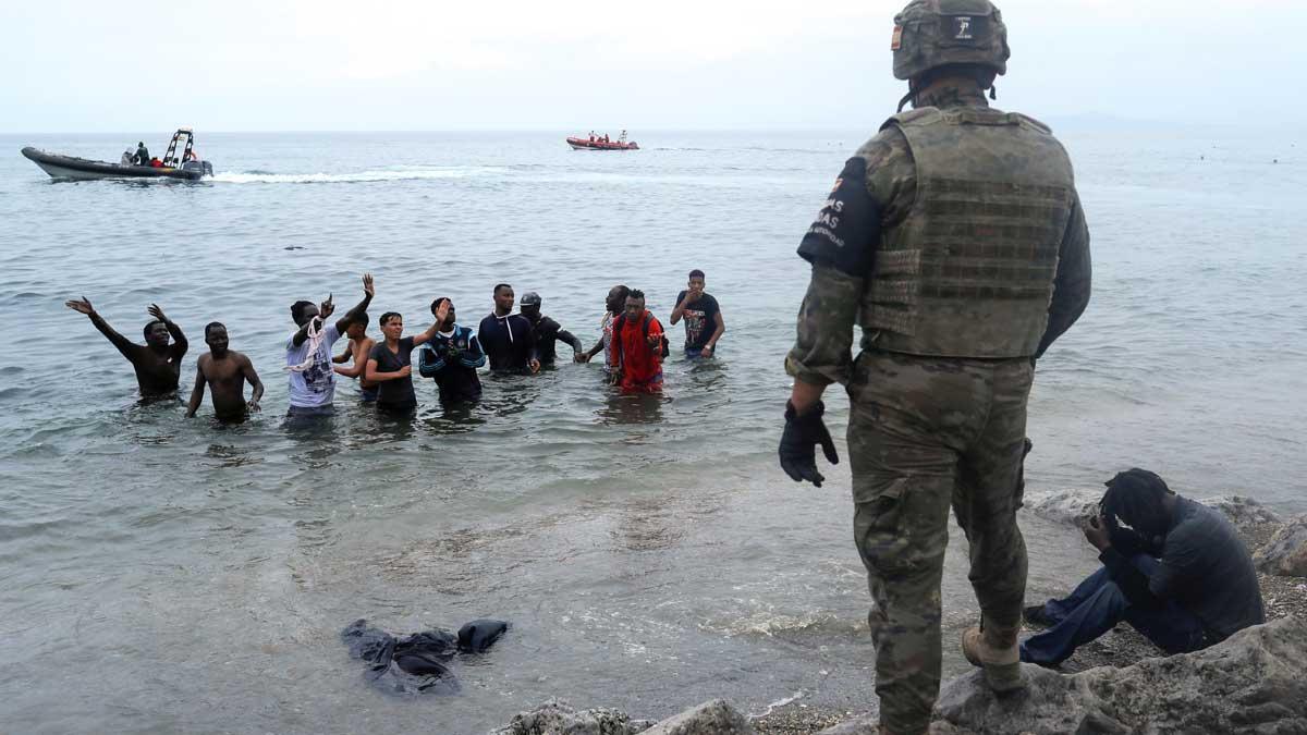 Un legionario español, frente a ciudadanos marroquís que intentaron entrar a nado a España cruzando la frontera en Ceuta.