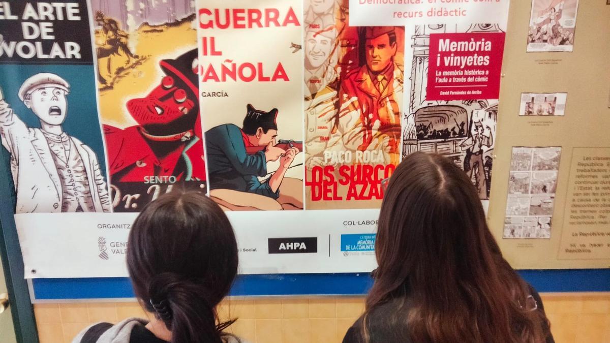 Dos alumnas del IES La Asunción de Elche miran los carteles de la exposición.