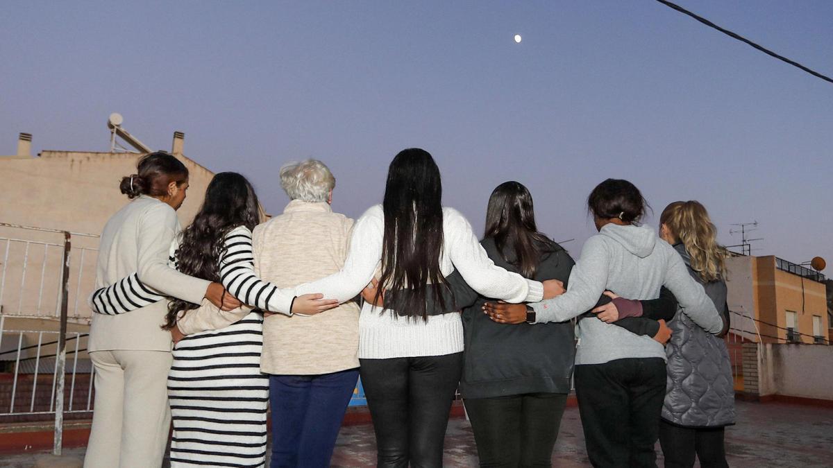 Las mujeres se abrazan, serenas, en la terraza de la casa de acogida Beto mientras atardece en la huerta murciana.