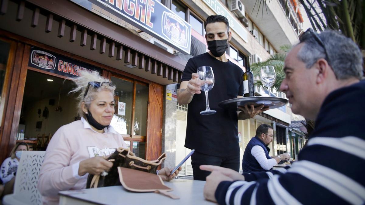 Un camarero atiende a dos clientes en una terraza de Santa Cruz.