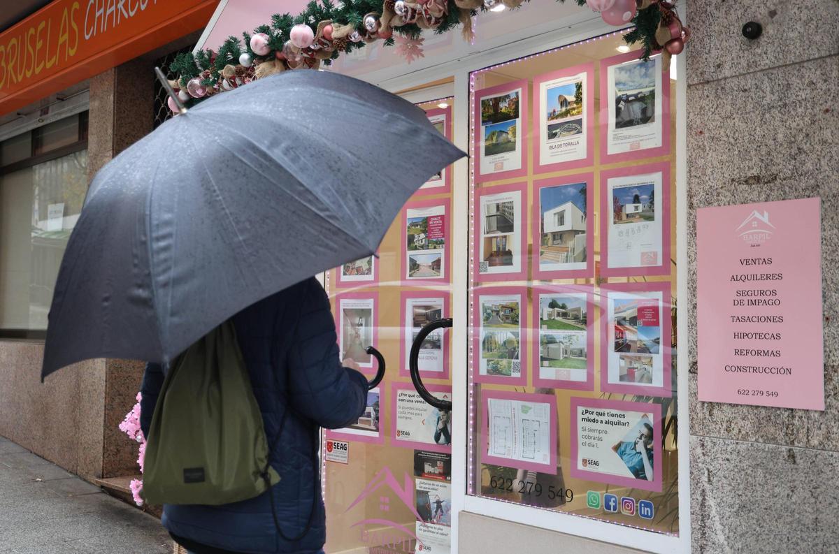 Una persona mirando el escaparate de una inmobiliaria en Vigo.