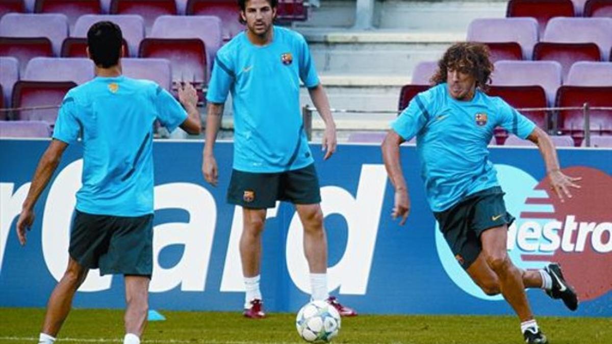 Busquets, de espaldas, Cesc y Puyol, en el ensayo de ayer.