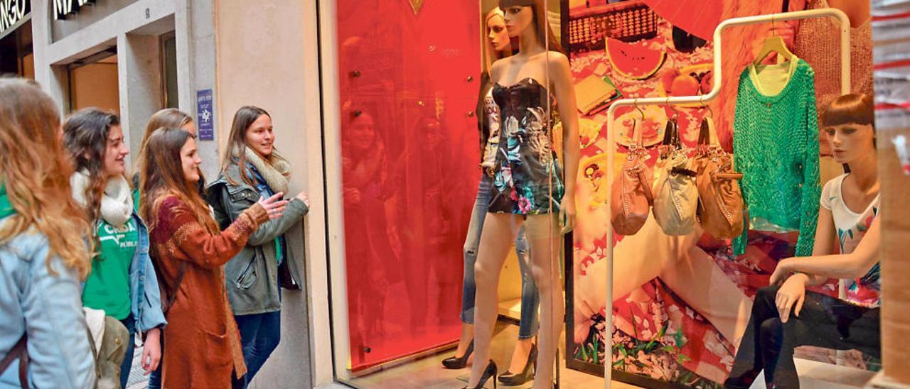 Un grupo de adolescentes observa un escaparate de una tienda de ropa femenina situada en el centro de Palma.