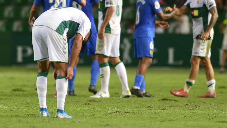 Jugadores del Elche y del Fuenlabrada se saludan al final del partido, con el césped levantado.