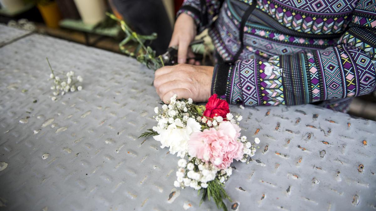 Una mujer deposita flores en una tumba.