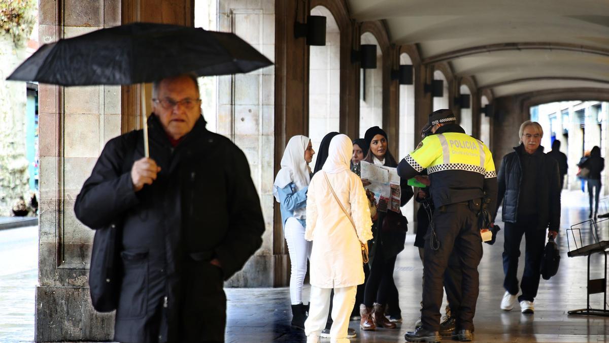 Turistas piden información a un agente de la Guardia Urbana de Barcelona.