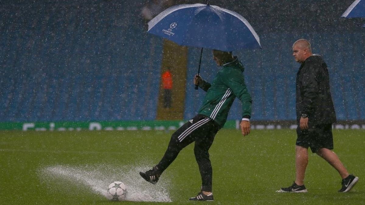 El árbitro, el holandés Kuipers, comprueba las dificultades para que ruede el balón, esta noche en el Etihad.