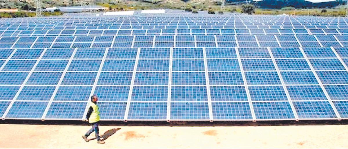 Un operario pasa ante una instalación de energía renovable en una planta fotovoltaica.