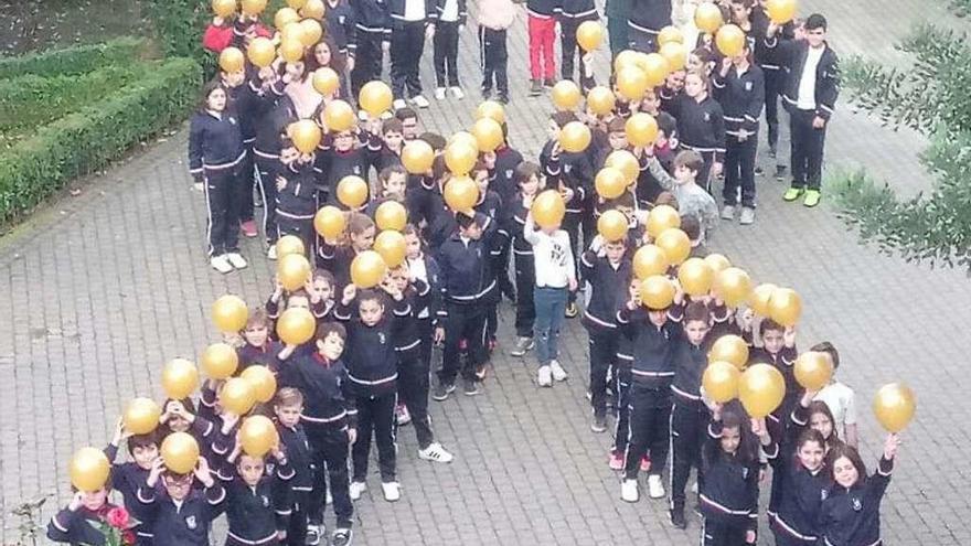 Los alumnos formaron en el patio con globos el lazo dorado de la lucha contra el cáncer infantil. // FdV