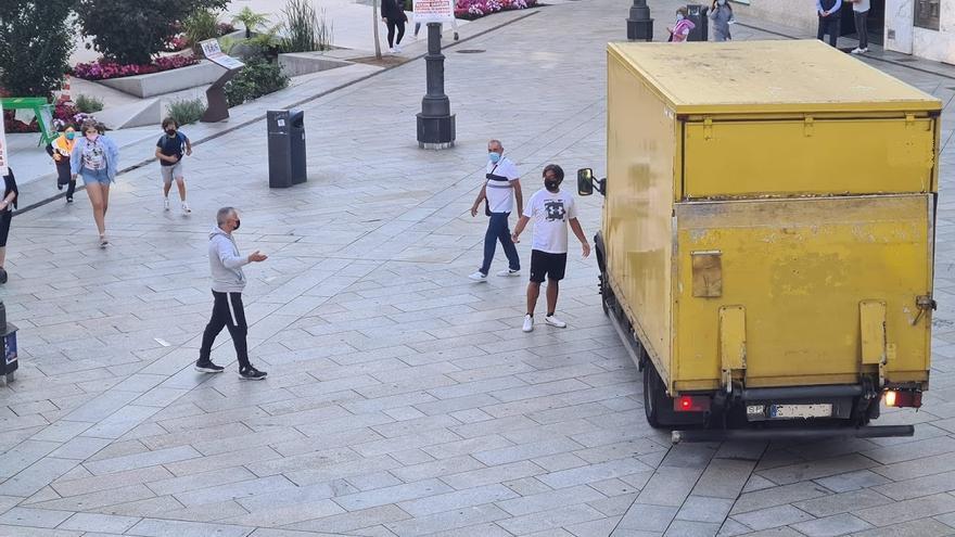 Varios viandantes reprochan la maniobra de un conductor que daba  marcha atrás en la plaza de Galicia, esta mañana.