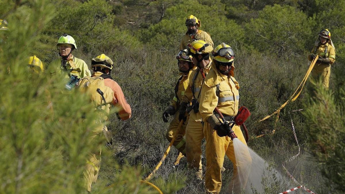 Trabajadores del Infoar refrescan una zona afectada por un incendio forestal.