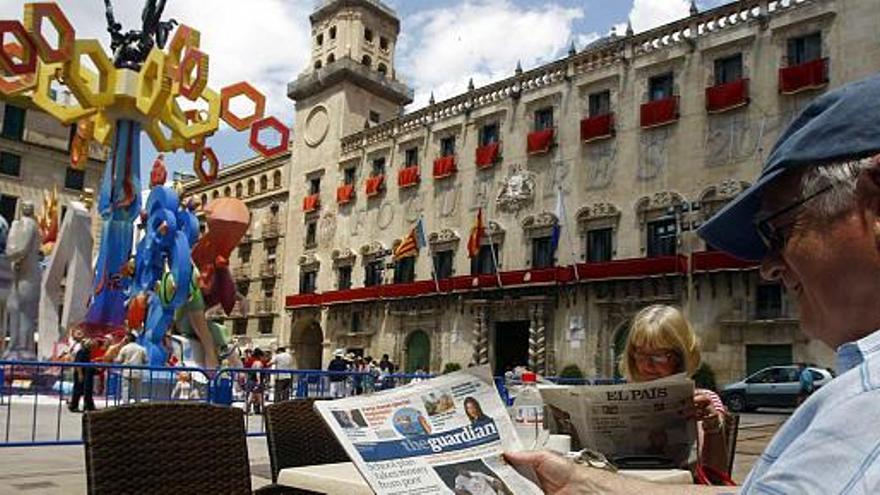 Una pareja de turistas lee la prensa, ayer, en la Plaza del Ayuntamiento a pocos metros de la Hoguera Oficial &quot;Amor de verano&quot; de Pedro Espadero, ya acabada.