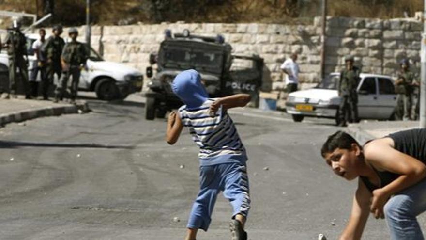 Jóvenes palestinos arrojan piedras contra los soldados israelíes.
