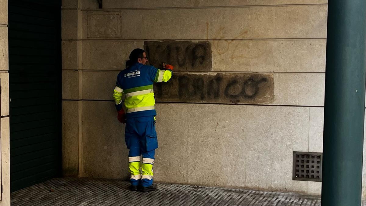 Un operario de Emaya borra una pintada que ha aparecido con la frase 'Viva Franco'.